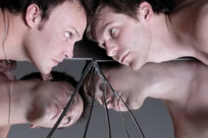 two men looking at each other across a broken mirror